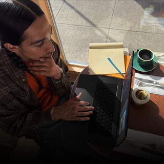 Una persona utiliza un MacBook Pro que no está enchufado a la corriente en una cafetería