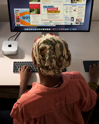 Una persona utiliza un Mac mini con Magic Keyboard, Magic Trackpad y Studio Display conectado en un escritorio
